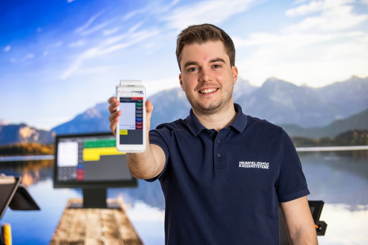 Benno Heimpel von POSSUM Kassensysteme hält ein mobiles all-in-one Kassensystem in der Hand